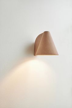 a wall mounted light on the side of a white wall next to a lamp shade