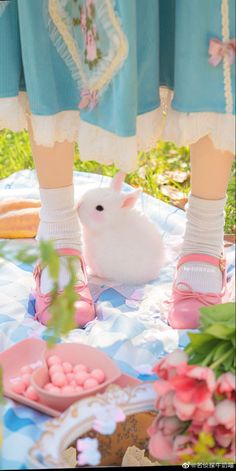 a white rabbit sitting on top of a table next to a person's legs