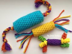 two crocheted toys are laying next to each other on a white surface, one is blue and the other is yellow