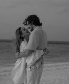 a man and woman kissing on the beach