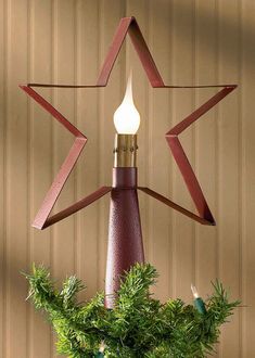 a star shaped light hanging from the side of a wooden pole in front of a wall