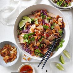 a white bowl filled with meat and veggies next to two bowls of sauce