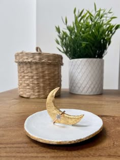 a white plate with a gold crescent ring on it next to a potted plant