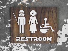 a wooden sign with the words rest room and star wars characters on it in white