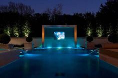 an outdoor movie screen in the middle of a swimming pool at night with lights on