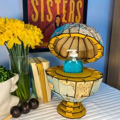 a table topped with books and vases filled with yellow flowers next to a lamp