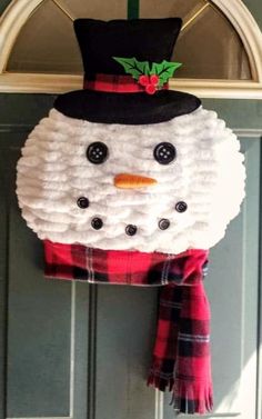 a snowman hat and scarf hanging on the front door to decorate it for christmas