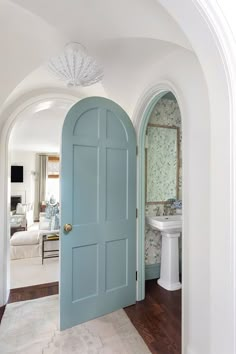 an archway leading to a bathroom with a sink and toilet in it, next to a blue door