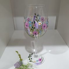 a wine glass with flowers painted on it