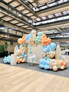 a large balloon arch is decorated with pastel blue, orange and white balloons in the shape of a surfboard