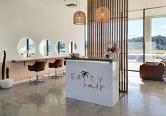 a hair salon with chairs and mirrors on the wall, along with an island counter