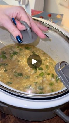 a woman is using a mouse to get food out of the slow cooker