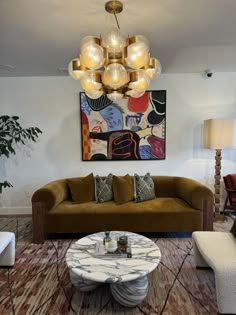 a living room filled with furniture and a painting hanging on the wall above it's coffee table