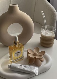 a white table topped with a vase and two small containers filled with liquid next to a tube of toothpaste