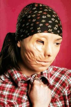 a woman wearing a bandana and holding her hands to her face