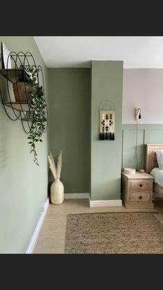 a bedroom with green walls and white bedding, wooden dressers and plant hanging on the wall