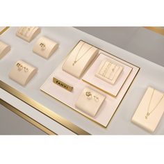 an assortment of jewelry is displayed on a white counter top with gold trimmings