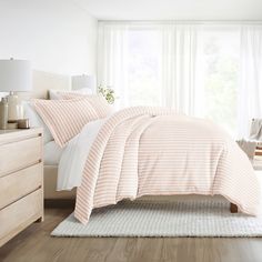 a bed with pink and white striped comforter in a bedroom