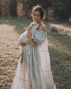 a woman in a white dress holding a sheep