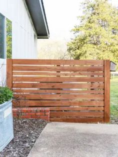 a wooden fence next to a house with potted plants on the side of it