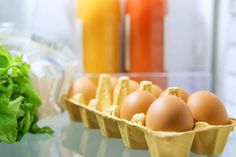 eggs in cartons lined up on a table next to vegetables and juices,