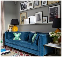 a living room filled with blue couches and pictures on the wall above each sofa