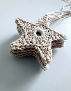 a crocheted star ornament hanging from a string on a white surface