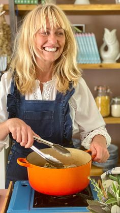 a woman in an apron is cooking on the stove with a pot and ladle