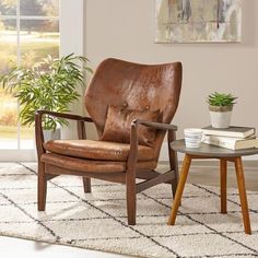 a brown leather chair sitting on top of a rug next to a table with a potted plant