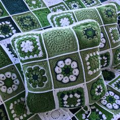 green and white crocheted afghan with flowers on the side, sitting on top of a couch