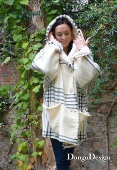 a woman is walking down the street with her hand up to her ear and wearing a coat