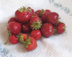 a pile of strawberries sitting on top of a bed