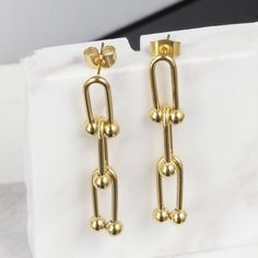 Introducing our stunning Emma U-Shaped Earrings, a unique and stylish accessory that is sure to make a statement. These earrings feature a beautiful and intricate design that is both contemporary and classic, making them perfect for any occasion. Crafted from high-quality materials and plated with 14K gold, these earrings are both beautiful and durable. The gold plating gives them a luxurious and sophisticated look that is sure to catch the eye of anyone who sees them. They are also incredibly l Elegant Dangle Earrings With Unique Design, Elegant Gold Earrings With Unique Design, Modern Drop Earrings With Unique Design, Modern Pierced Chandelier Earrings As Gift, Modern Gift Chandelier Earrings, Statement Earrings Gold, Gold Statement Earrings, Intricate Design, Stylish Accessories