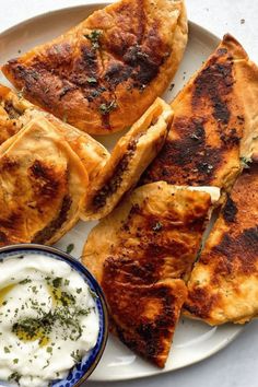 some pita breads on a plate with yogurt and sour cream sauce