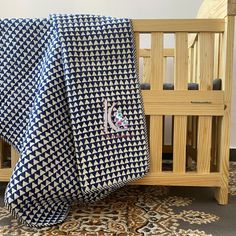 a blue and white blanket sitting on top of a wooden crib