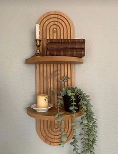 a wooden shelf with some plants and candles on it, next to a candle holder