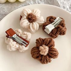 three crocheted hair clips sitting on top of a white plate next to some yarn