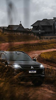 a black car is parked on a dirt road