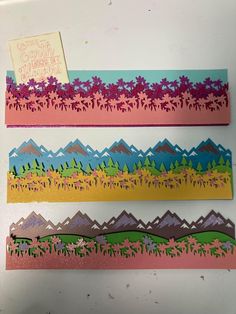 three pieces of paper with mountains and trees on them