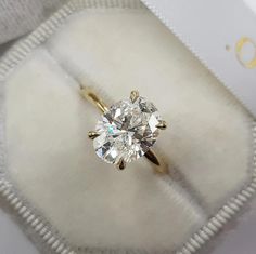 an engagement ring with a diamond in it on a white velvet box and gold lettering