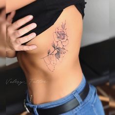 a woman's stomach with a rose tattoo on her lower back and the side