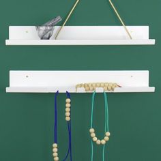 two white shelves with necklaces hanging from them and a bird perched on the shelf