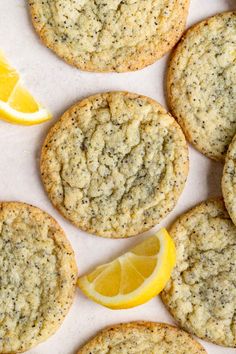 lemon and poppy seed cookies are arranged on a white surface with slices of lemon next to them