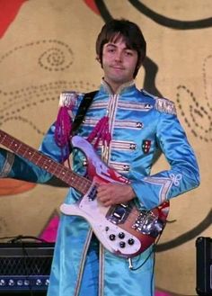 a man in blue outfit playing an electric guitar