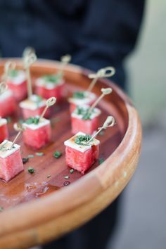 small appetizers are arranged on a wooden tray with green garnishes