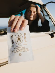 a woman holding up a piece of paper in front of her face while sitting in the back of a pickup truck