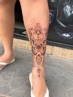 a woman's leg with a tattoo on it that has flowers and leaves in the center