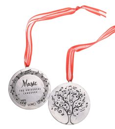 two medals with red ribbons around them on a white background, one has a tree and the other is music