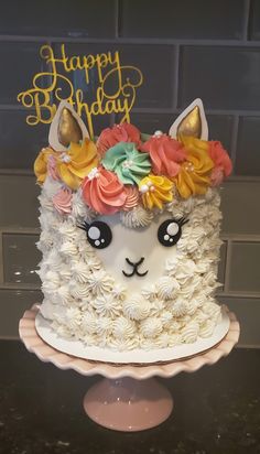 a birthday cake decorated with an alpaca and flowers