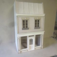 a white doll house with windows and shutters